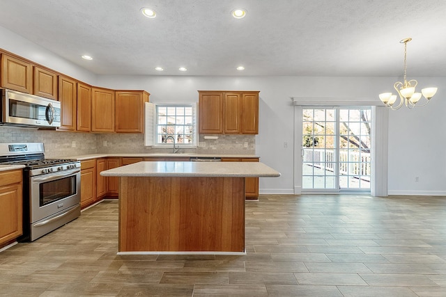 kitchen with a sink, light countertops, appliances with stainless steel finishes, and a kitchen island