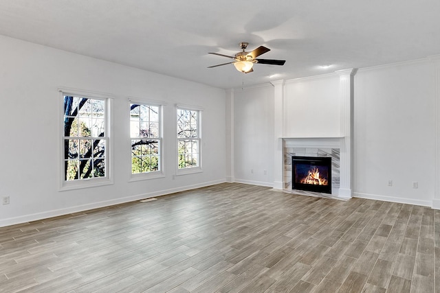 unfurnished living room with light wood-style floors, a fireplace, baseboards, and a ceiling fan