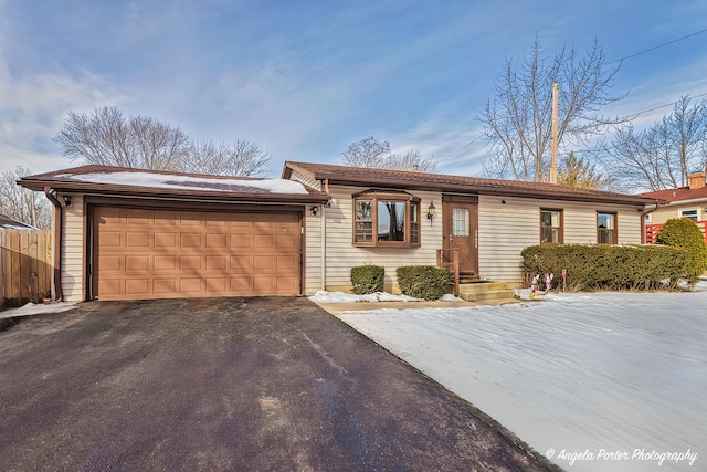 ranch-style house featuring a garage, driveway, and fence