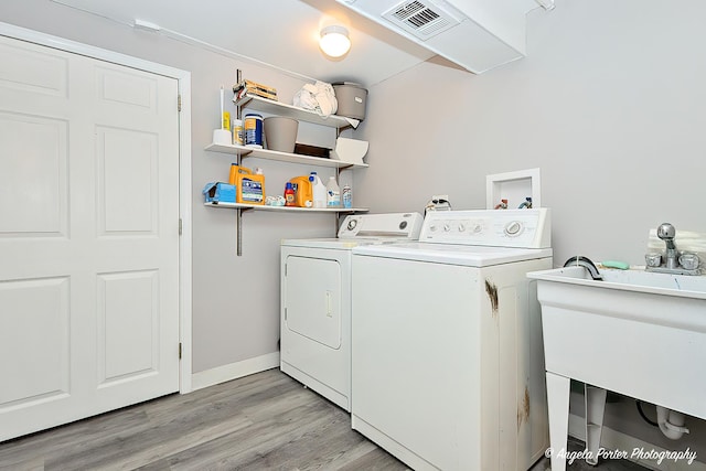 laundry area with laundry area, a sink, visible vents, light wood-type flooring, and washing machine and clothes dryer