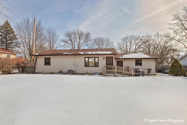 snow covered property with central AC unit, fence, and a deck