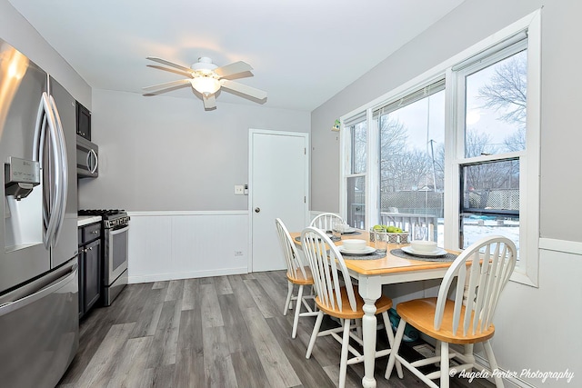 dining area with ceiling fan, dark wood finished floors, and wainscoting