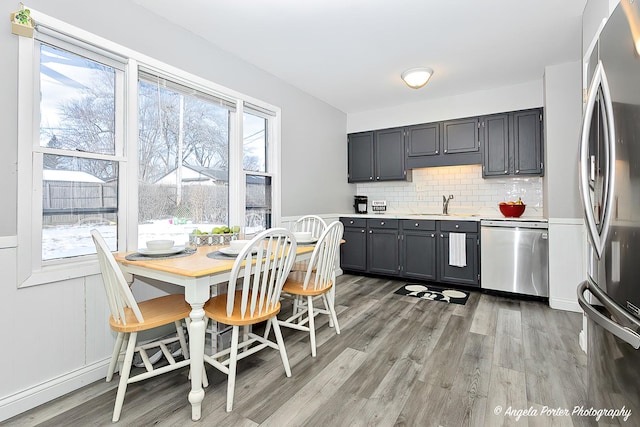 kitchen with stainless steel appliances, light countertops, light wood-style flooring, decorative backsplash, and a sink