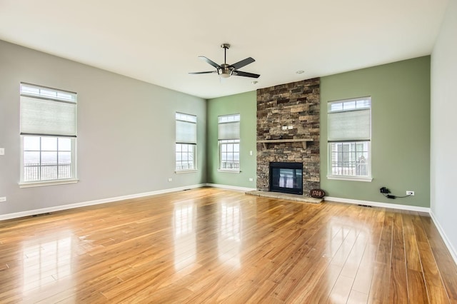 unfurnished living room featuring hardwood / wood-style floors, a fireplace, baseboards, and a ceiling fan