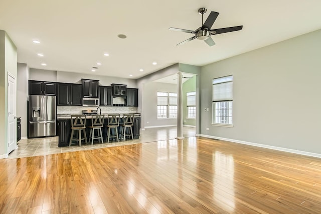 living area with recessed lighting, baseboards, light wood-style floors, and ornate columns