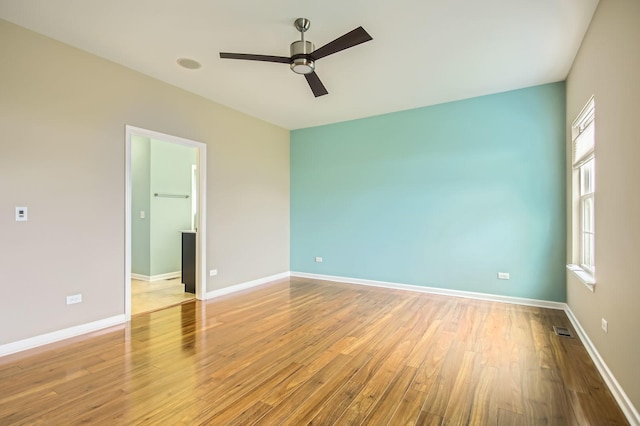 spare room with wood finished floors, visible vents, a wealth of natural light, and baseboards