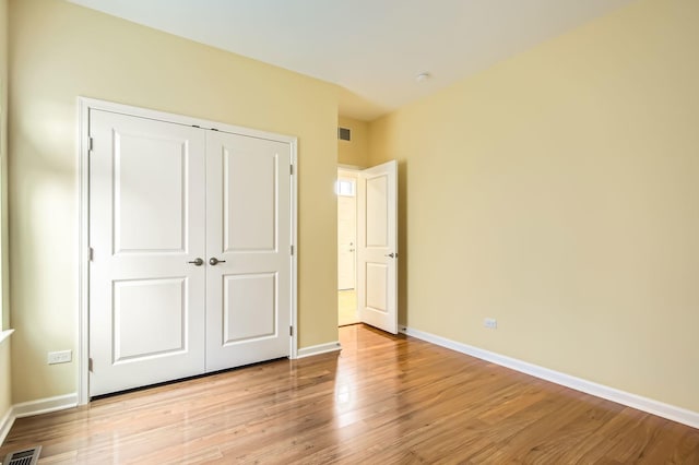 unfurnished bedroom featuring baseboards, visible vents, a closet, and light wood-type flooring