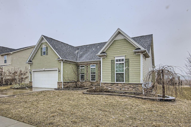 view of front of house featuring stone siding, driveway, and a garage