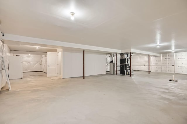 unfinished below grade area featuring gas water heater and freestanding refrigerator