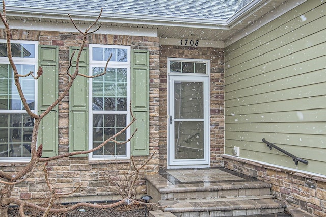 doorway to property with stone siding and roof with shingles