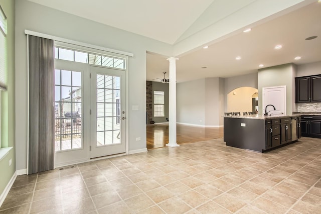 kitchen with ornate columns, recessed lighting, a sink, vaulted ceiling, and tasteful backsplash