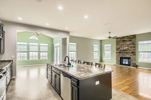 kitchen with recessed lighting, a kitchen island with sink, a sink, appliances with stainless steel finishes, and open floor plan