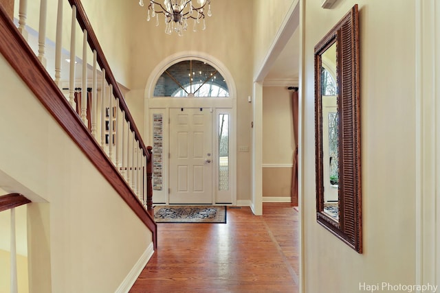 foyer entrance featuring baseboards, a high ceiling, stairway, and wood finished floors