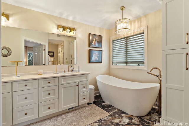 full bathroom with a soaking tub, a healthy amount of sunlight, vanity, and an inviting chandelier