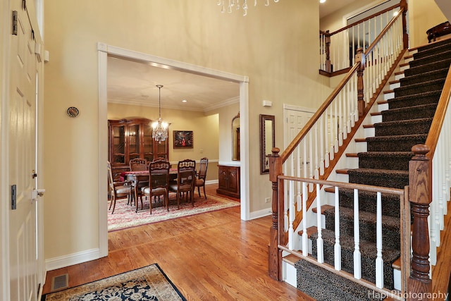 foyer entrance featuring crown molding, baseboards, light wood-style flooring, and a notable chandelier