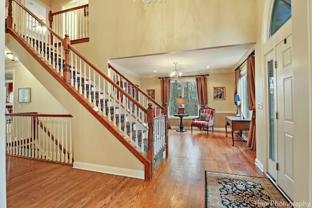 entrance foyer with baseboards, a high ceiling, ornamental molding, and wood finished floors