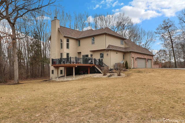 back of house featuring a lawn, a chimney, an attached garage, stairs, and a deck