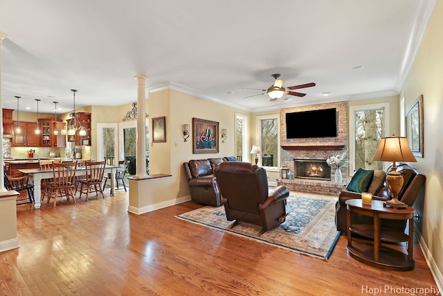 living area with a brick fireplace, light wood-style flooring, baseboards, and ceiling fan