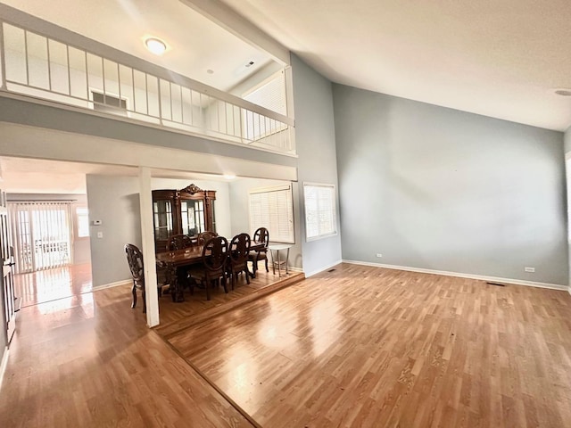 living room with high vaulted ceiling, visible vents, baseboards, and wood finished floors