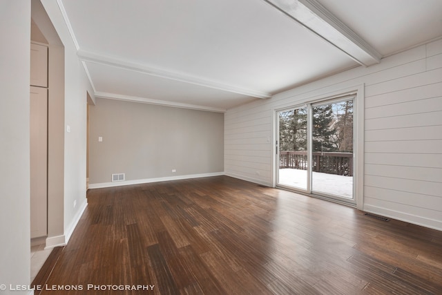 spare room featuring dark wood-style floors, baseboards, visible vents, and beam ceiling