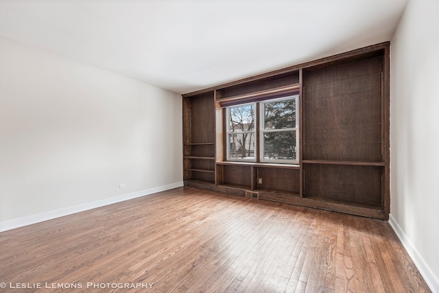 empty room with wood-type flooring and baseboards