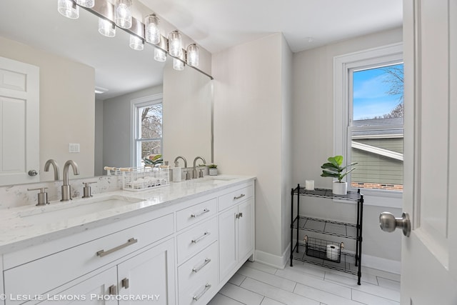 bathroom featuring a sink, baseboards, and double vanity