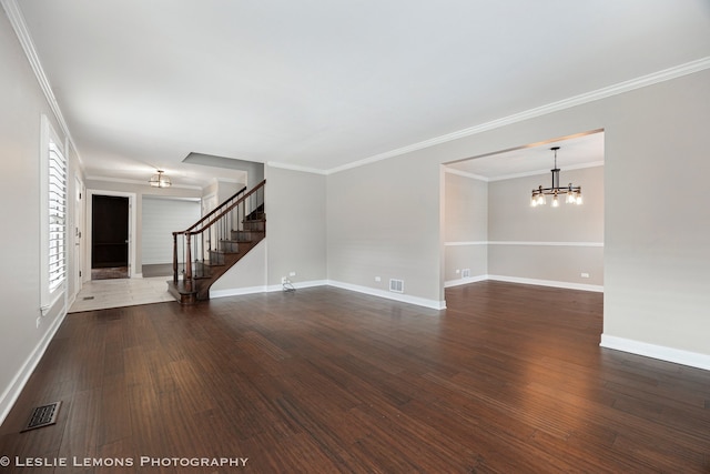 unfurnished room with wood finished floors, visible vents, a notable chandelier, and stairs