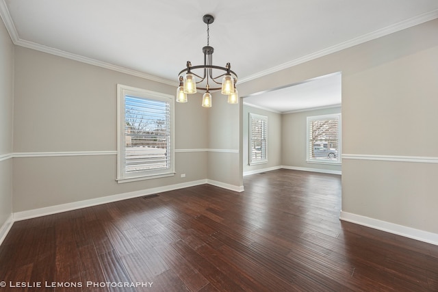 empty room featuring plenty of natural light, baseboards, wood finished floors, and ornamental molding