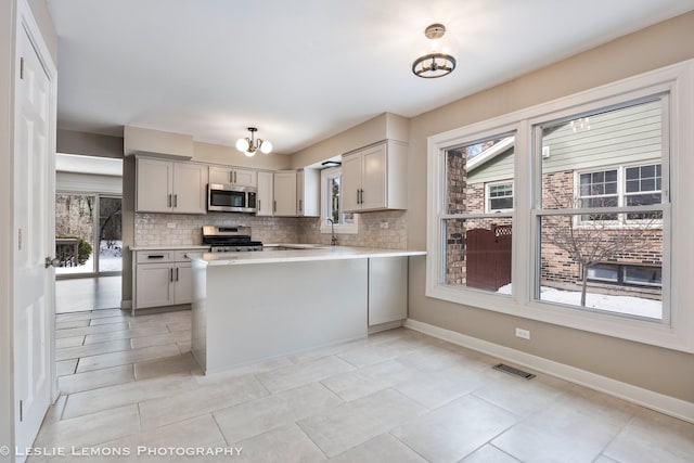 kitchen featuring light countertops, appliances with stainless steel finishes, visible vents, and decorative backsplash