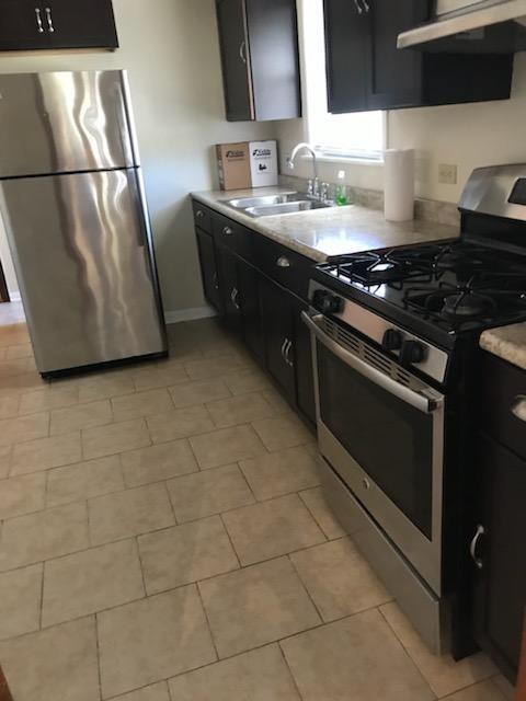 kitchen featuring a sink, stainless steel appliances, light countertops, and under cabinet range hood