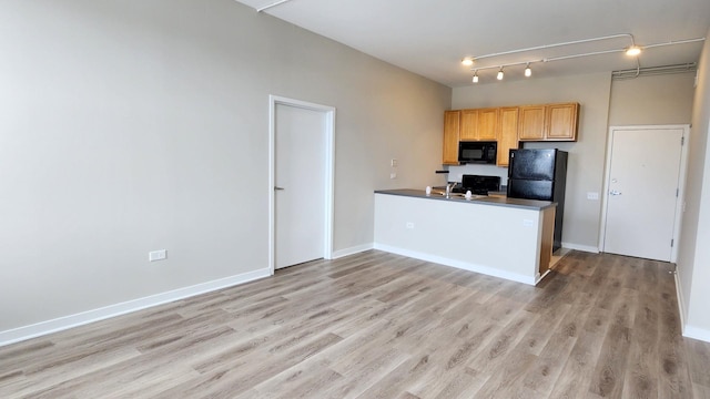 4015 N Milwaukee Ave Unit 516, Chicago, IL 60641 - kitchen with baseboards, dark countertops, a peninsula, black appliances, and light wood-style flooring