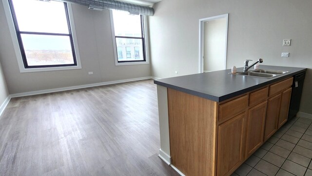 4015 N Milwaukee Ave Unit 516, Chicago, IL 60641 - kitchen with black dishwasher, a sink, dark countertops, light wood finished floors, and baseboards