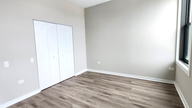 4015 N Milwaukee Ave Unit 516, Chicago, IL 60641 - unfurnished bedroom featuring a closet, baseboards, and wood finished floors