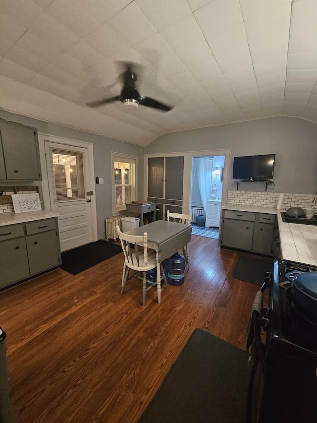 dining area featuring vaulted ceiling, radiator heating unit, dark wood finished floors, and a ceiling fan