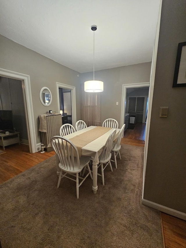 dining room featuring dark wood-style floors, baseboards, and dark carpet