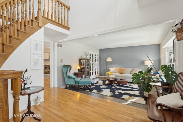 living area with a brick fireplace, wood finished floors, visible vents, and baseboards