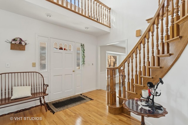 entryway featuring stairs, wood finished floors, and a towering ceiling