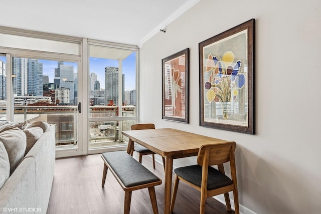 dining room with baseboards, wood finished floors, a view of city, crown molding, and floor to ceiling windows