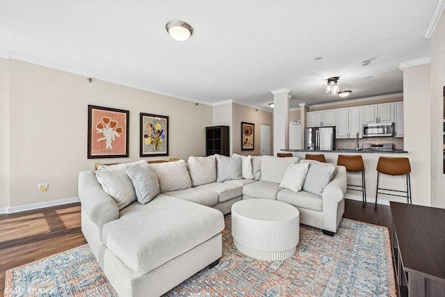 living room featuring baseboards, ornamental molding, dark wood-type flooring, and ornate columns