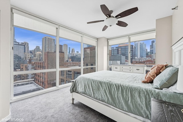 carpeted bedroom featuring a view of city, ceiling fan, and a wall of windows