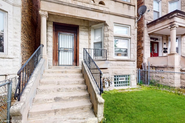 doorway to property featuring stone siding and fence