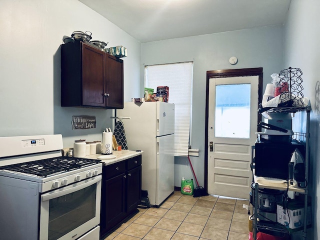 kitchen with white appliances, light tile patterned floors, light countertops, and dark brown cabinets