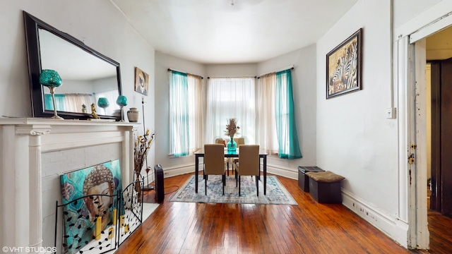 dining space with a brick fireplace, baseboards, and hardwood / wood-style floors