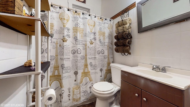 bathroom featuring backsplash, vanity, toilet, and tile walls