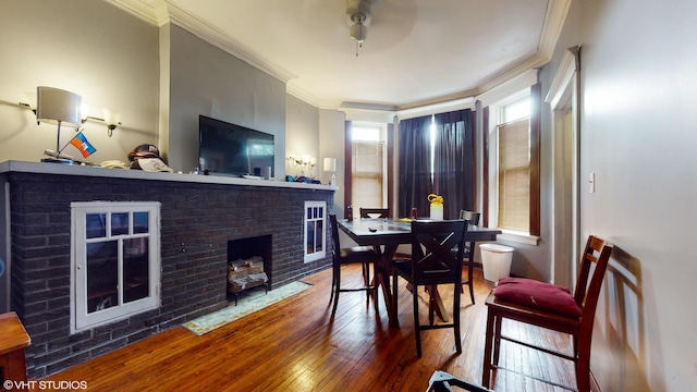 dining area with hardwood / wood-style floors, a fireplace, and crown molding