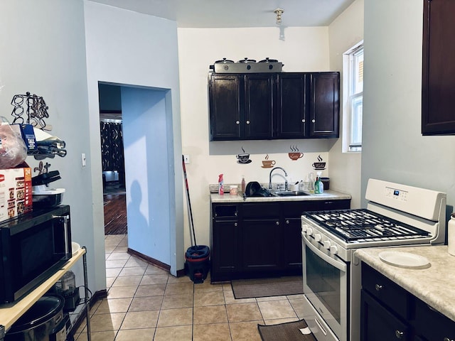 kitchen with black microwave, light countertops, a sink, and gas range gas stove