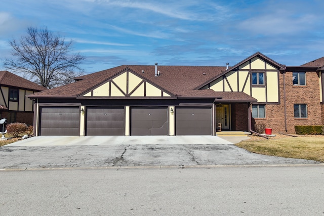 tudor home featuring a shingled roof and brick siding