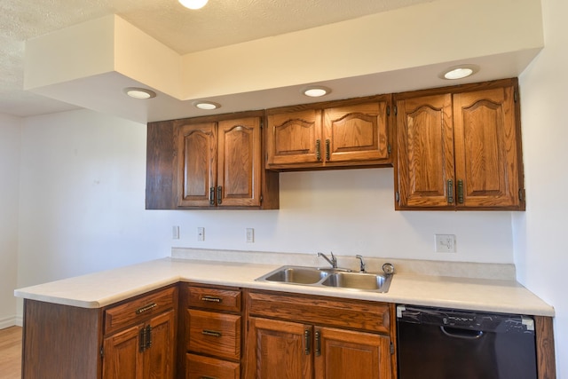 kitchen featuring black dishwasher, light countertops, a sink, and a peninsula