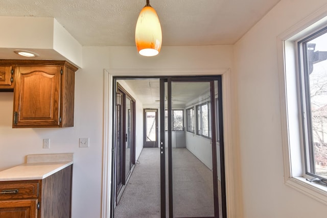 hallway with light carpet and a textured ceiling