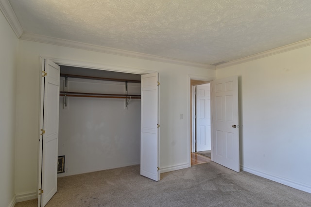 unfurnished bedroom with a textured ceiling, a closet, crown molding, and light colored carpet